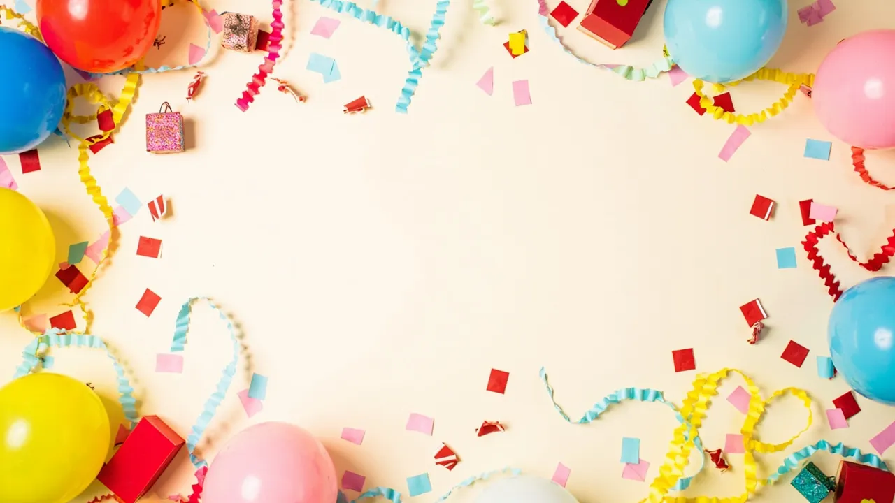 Buntes Flatlay aus Ballons, Konfetti und kleinen Geschenken